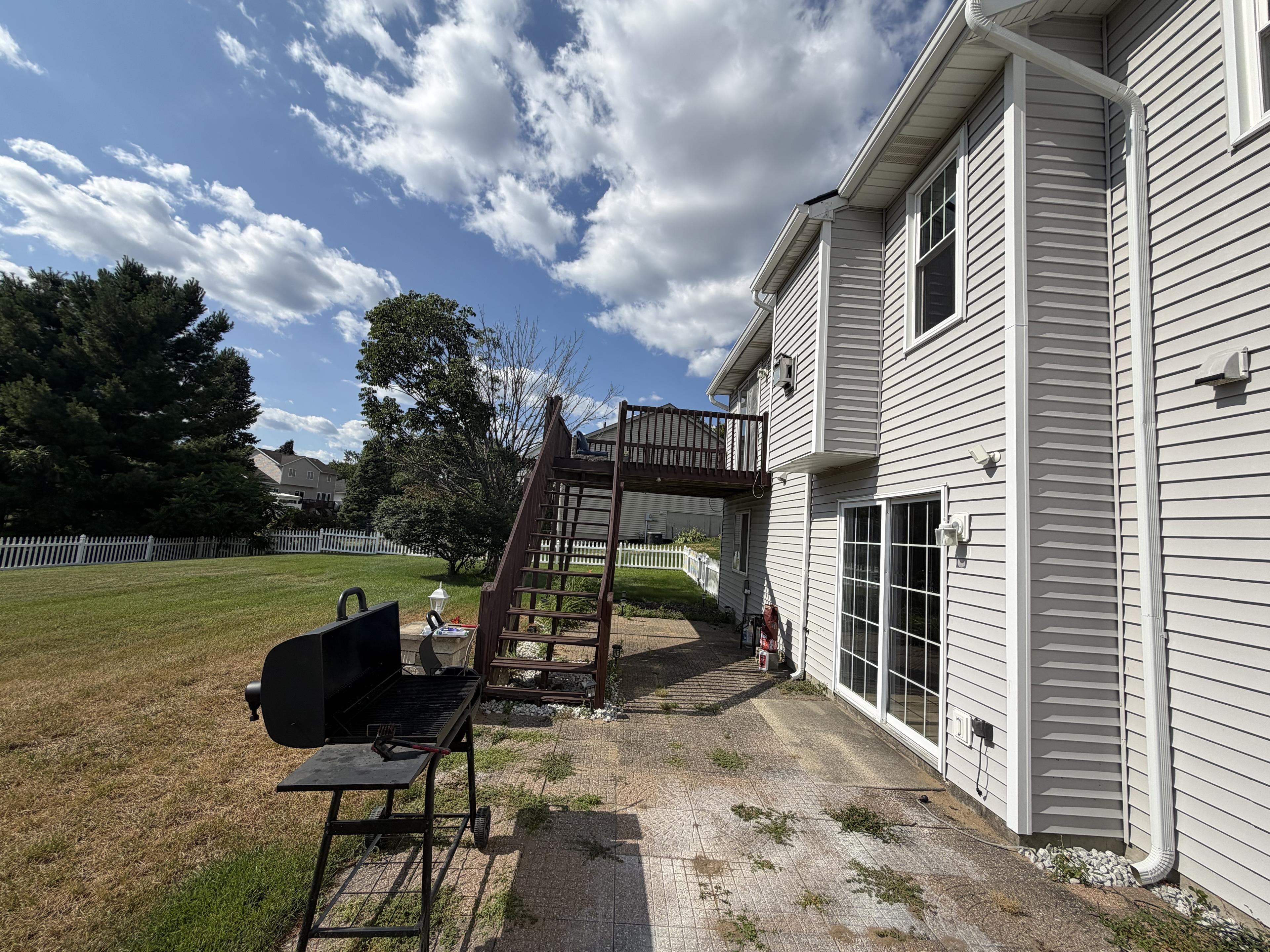 Backyard patio with a grill and stairs up to the raised deck