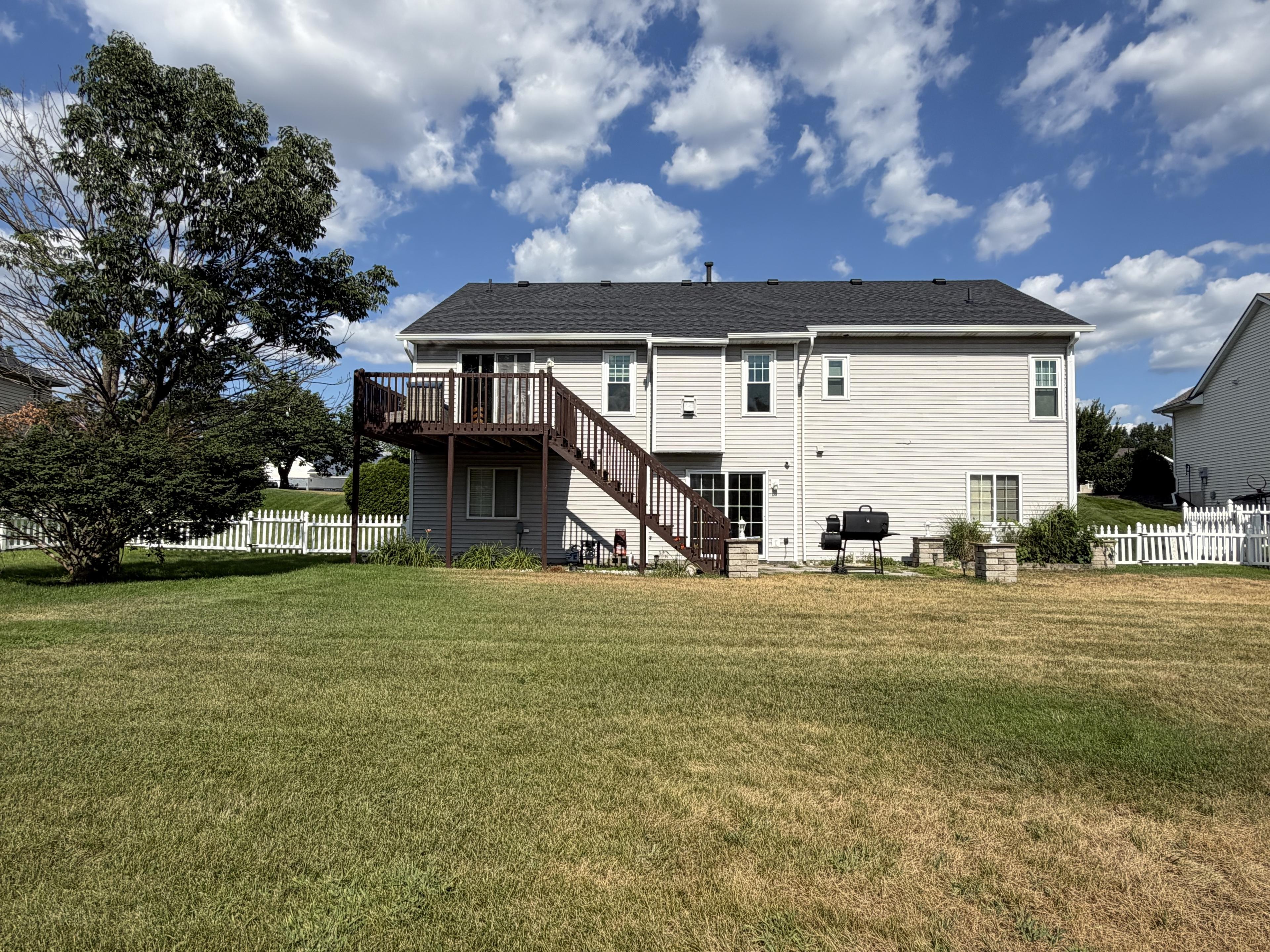 Wide backyard lawn with mature shade trees behind the home