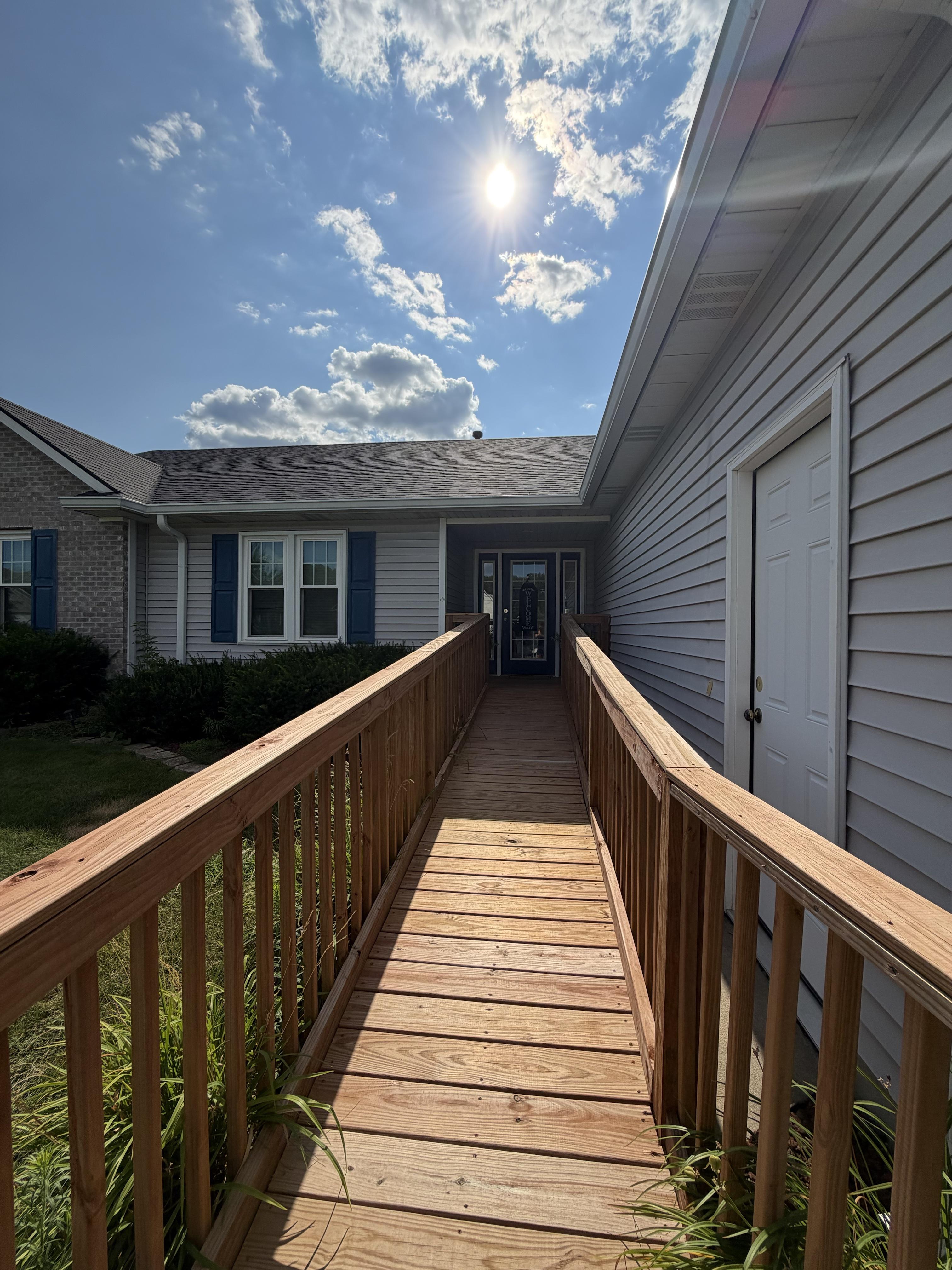Wheelchair ramp with handrails leading along the house to the entry door