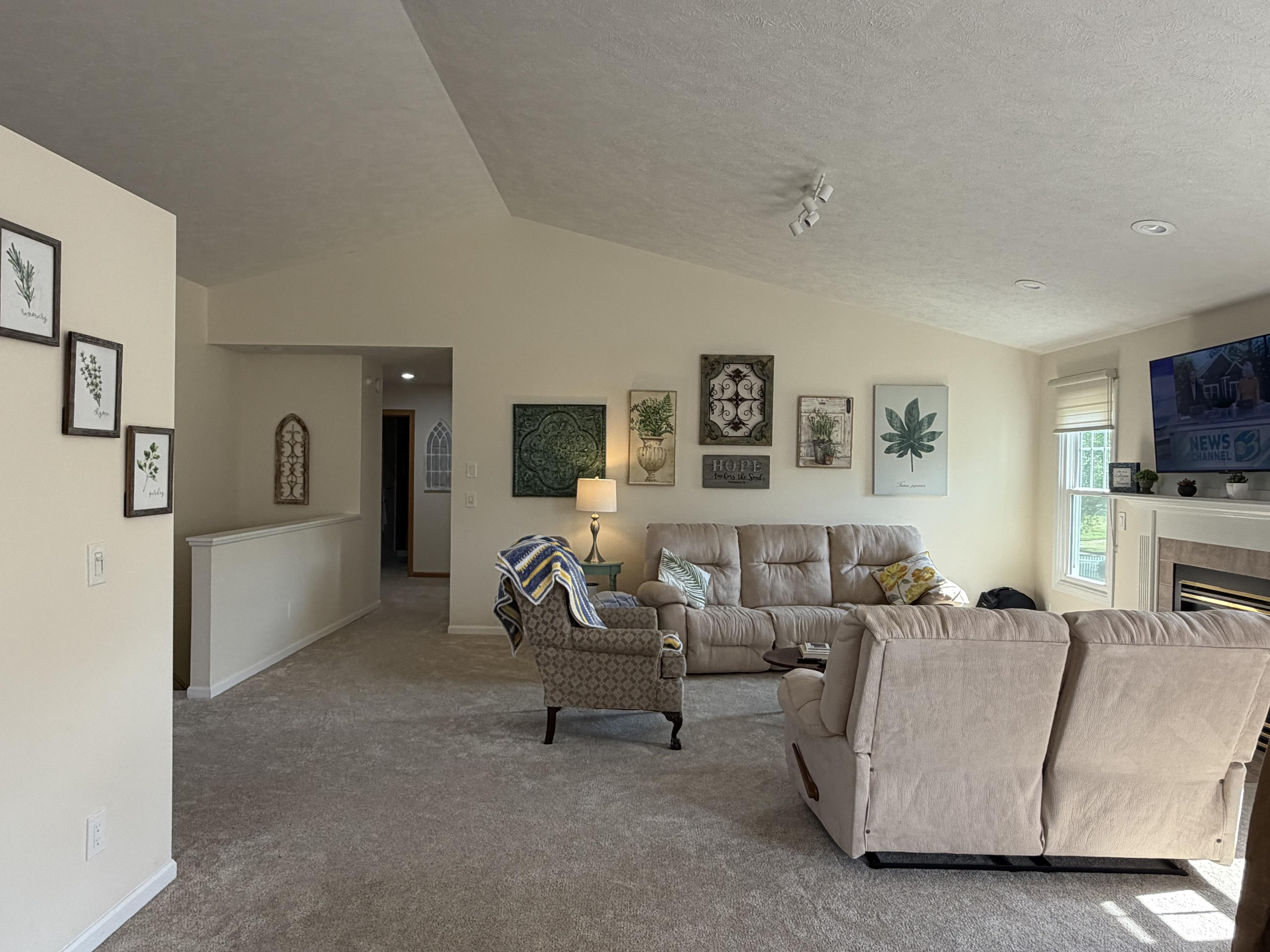 Shared living room with recliner seating, framed botanical art, and a fireplace