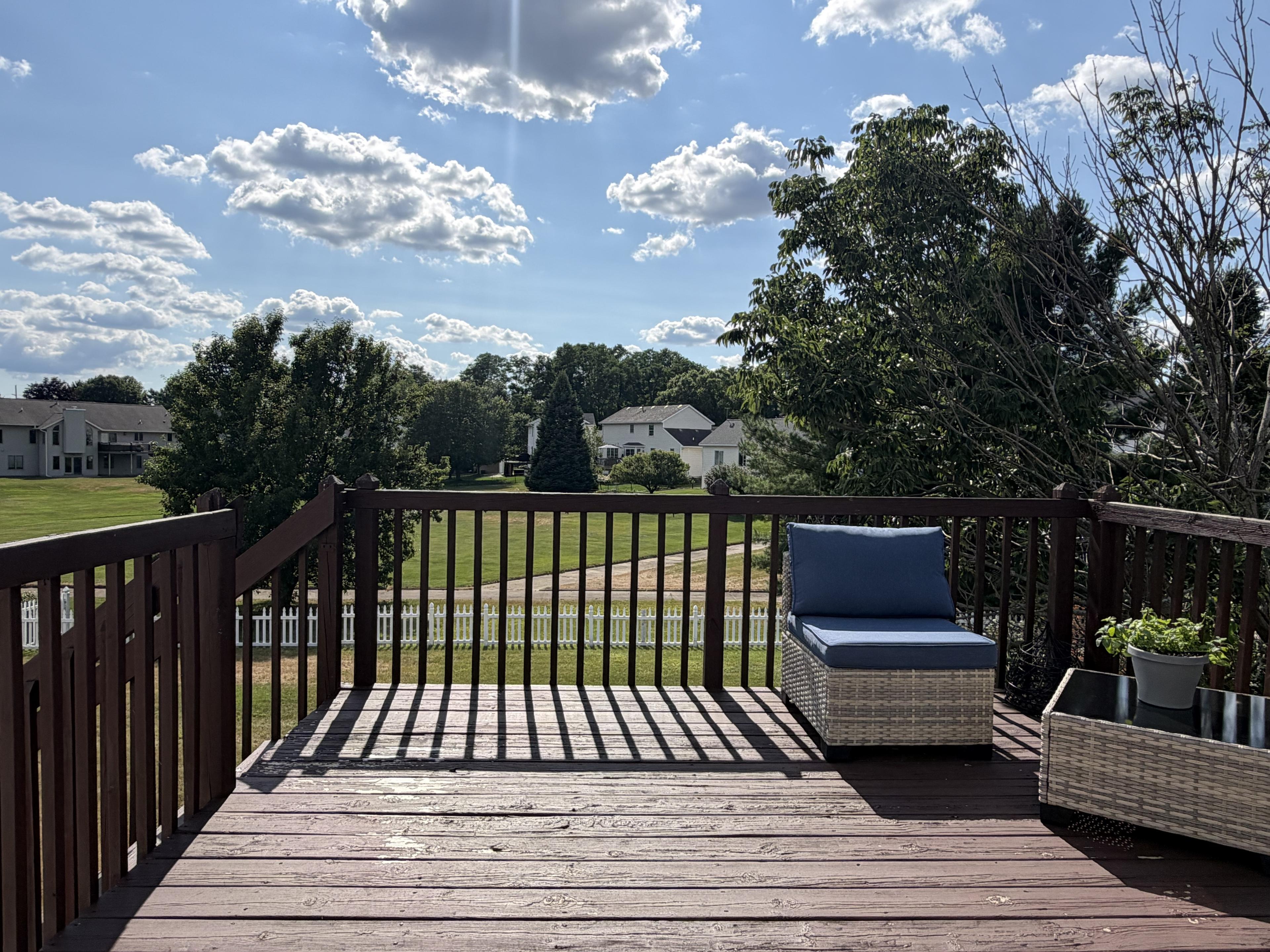 Back deck with cushioned seating and planters overlooking the neighborhood