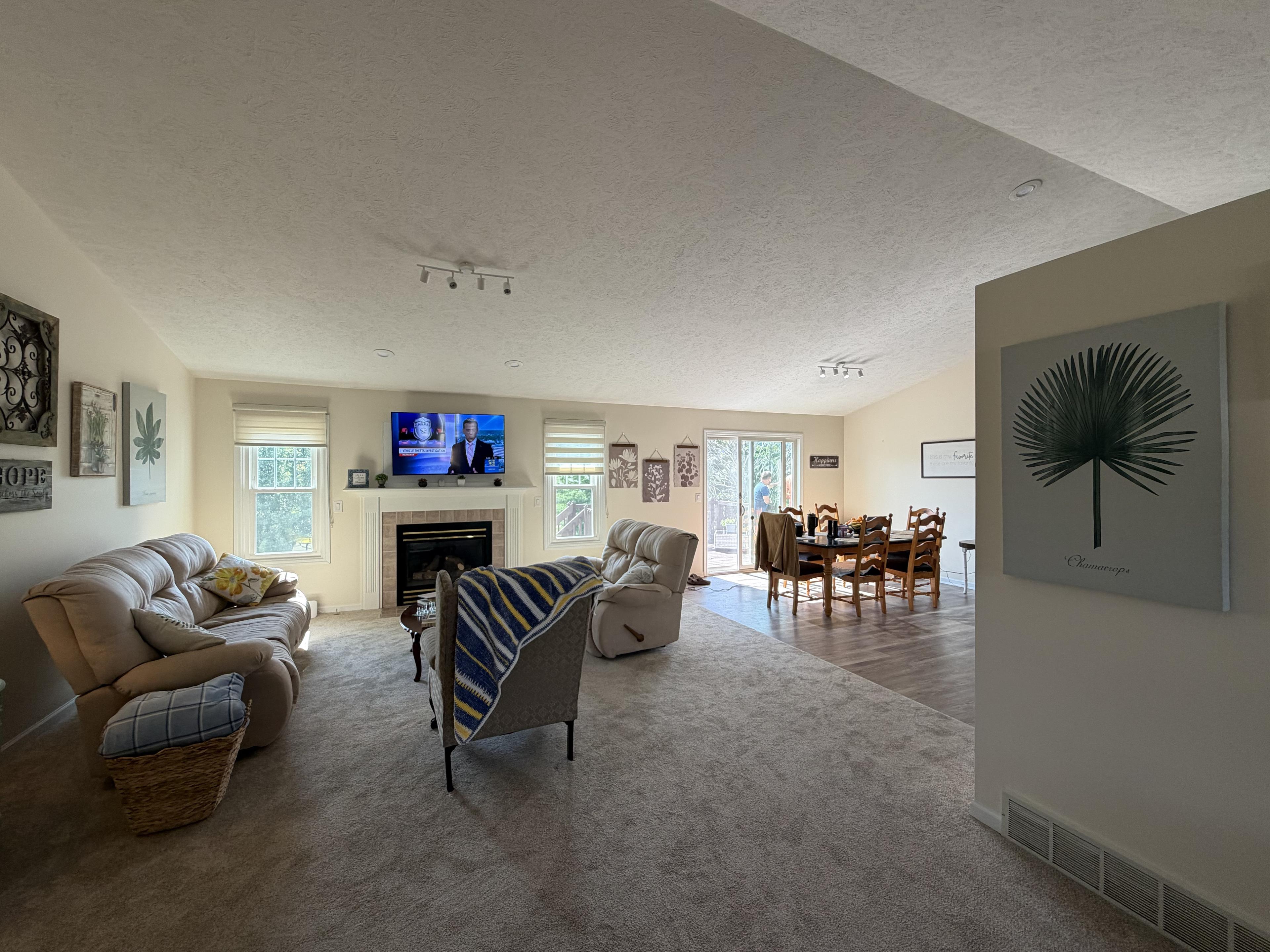 Living room with a fireplace and television, opening onto the dining area